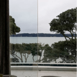 View through glass doors to a balcony with glass balustrades overlooking the sea. Glass balustrades New Plymouth.